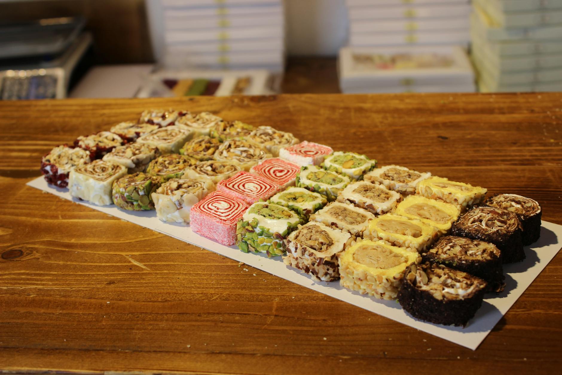 Verschiedene handgemachte Lokum-Rollen mit Nüssen und bunten Füllungen auf Holzgrund.