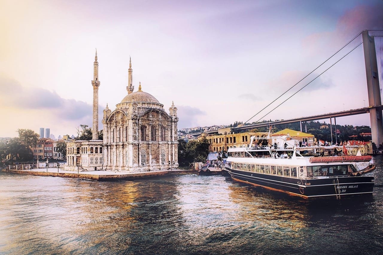 Ausflugsboot fährt auf dem Bosporus an der Ortaköy-Moschee vorbei.