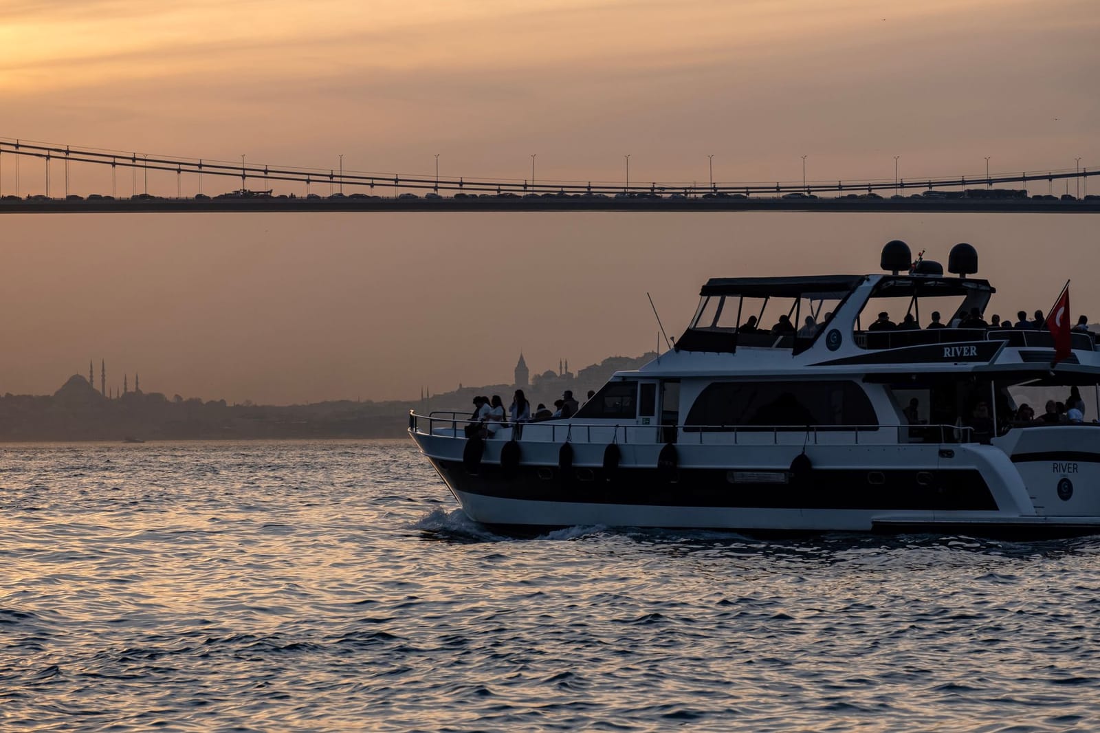 Ein Ausflugsschiff fährt bei Sonnenuntergang über den Bosporus in Istanbul.