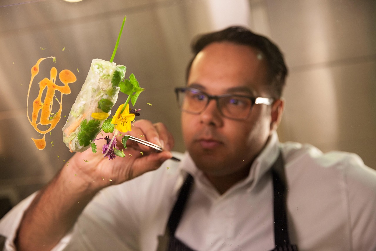 Chefkoch Fatih Tutak dekoriert ein kunstvolles Gericht mit essbaren Blüten und frischen Kräutern.