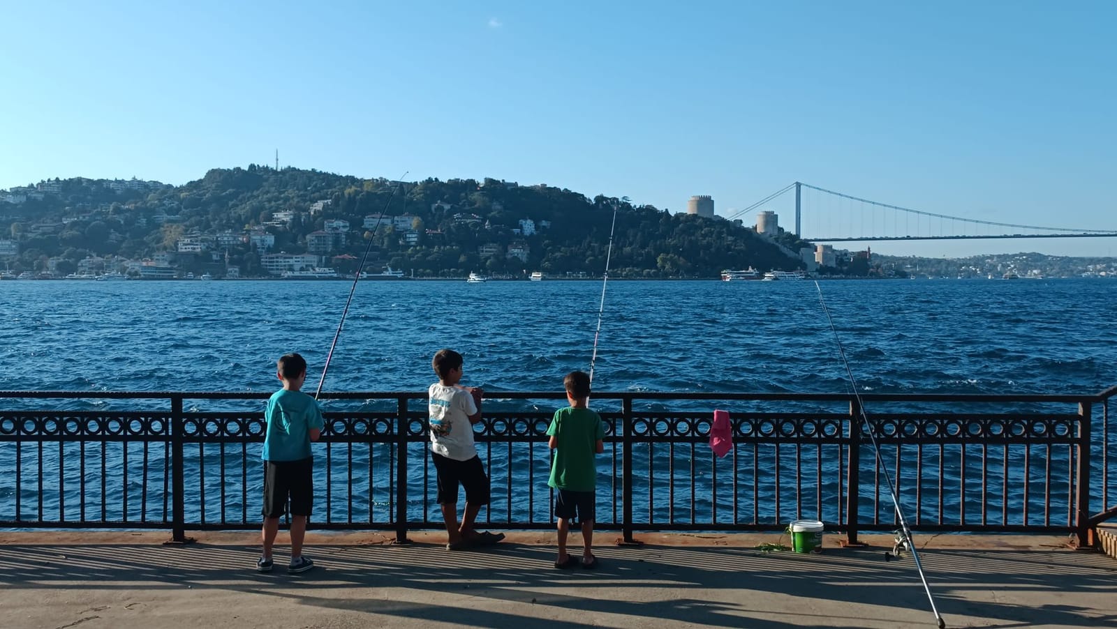 Drei Jungen angeln gemeinsam an der Uferpromenade des Bosporus.