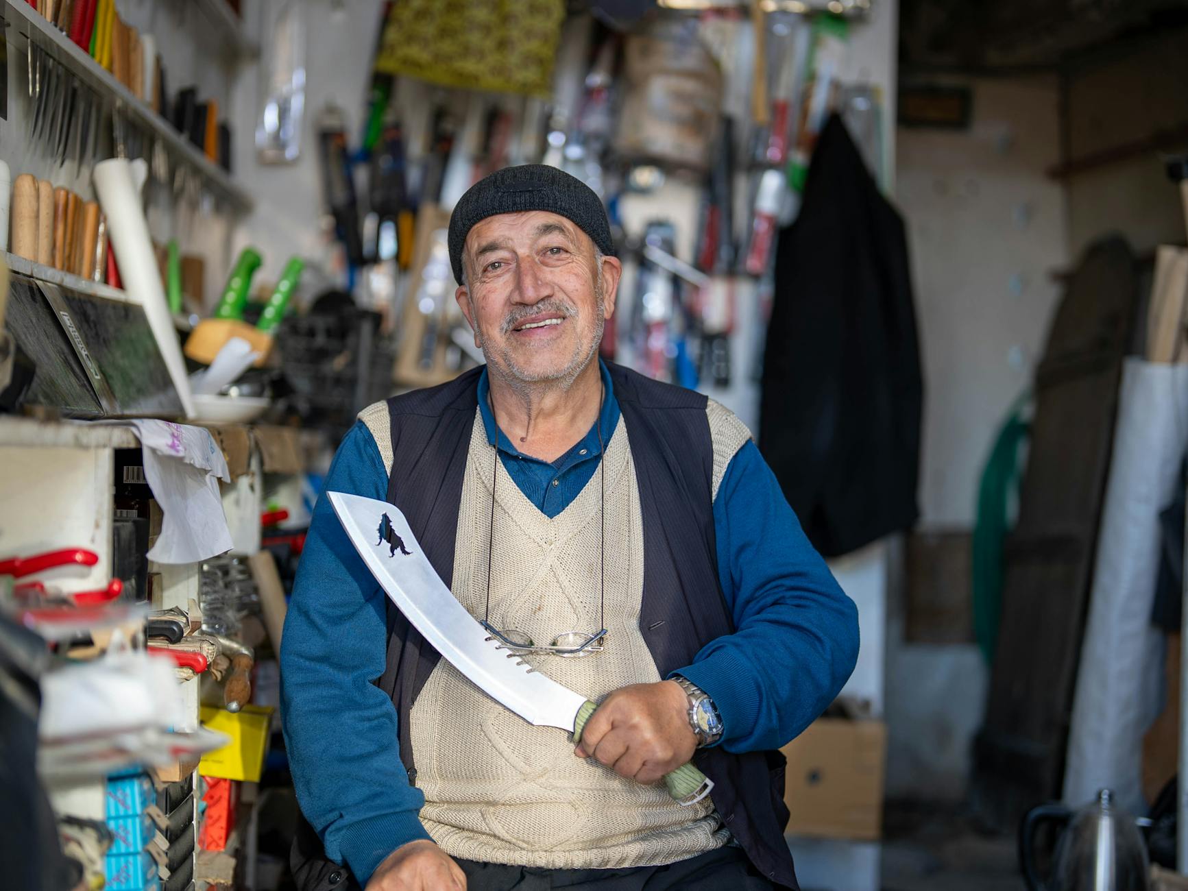 Ein lächelnder Handwerker präsentiert ein großes Messer in seiner Werkstatt im Großen Basar.