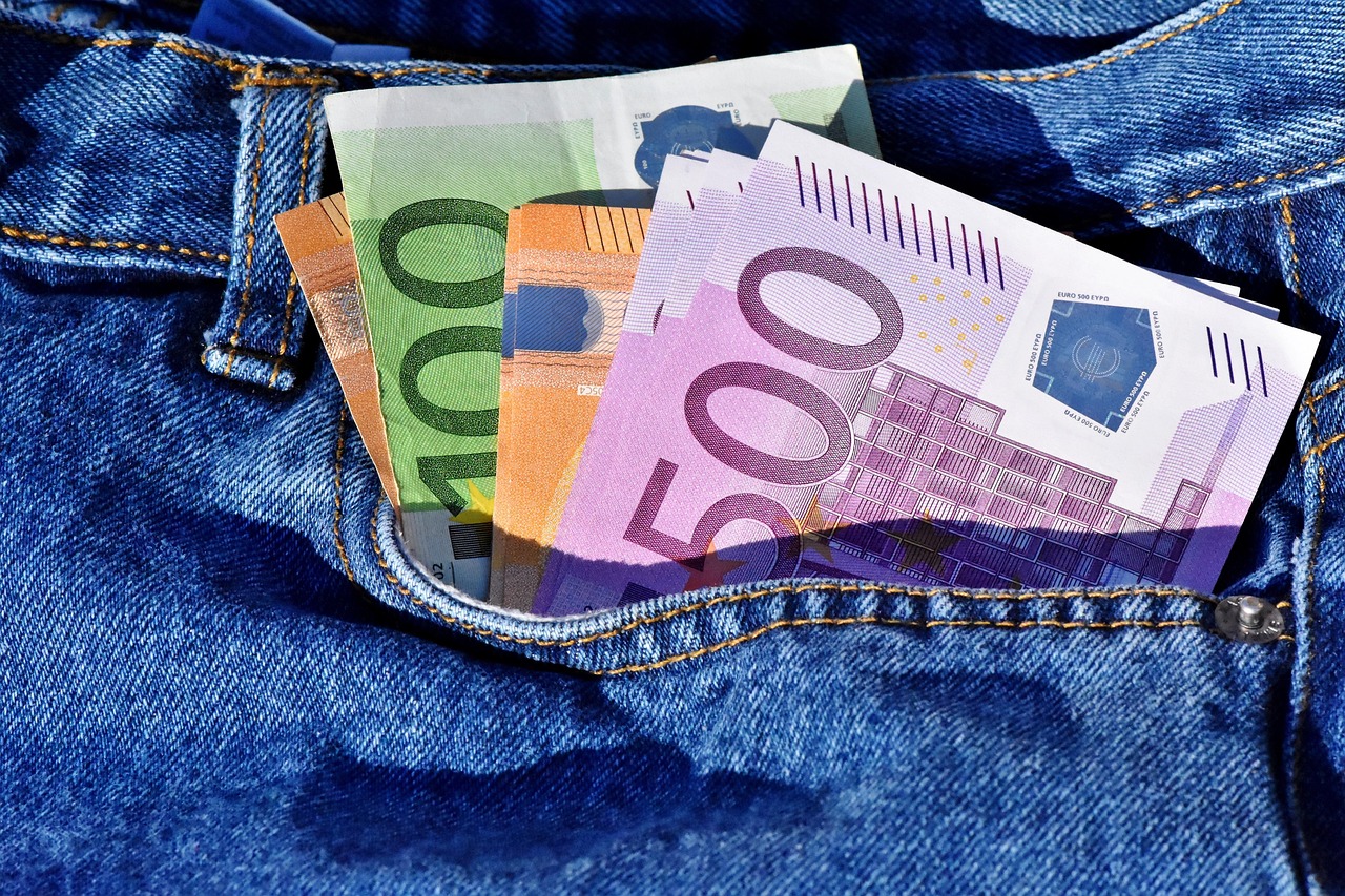Verschiedene Euro-Scheine als Reisebudget stecken sichtbar in der Tasche einer Jeans.