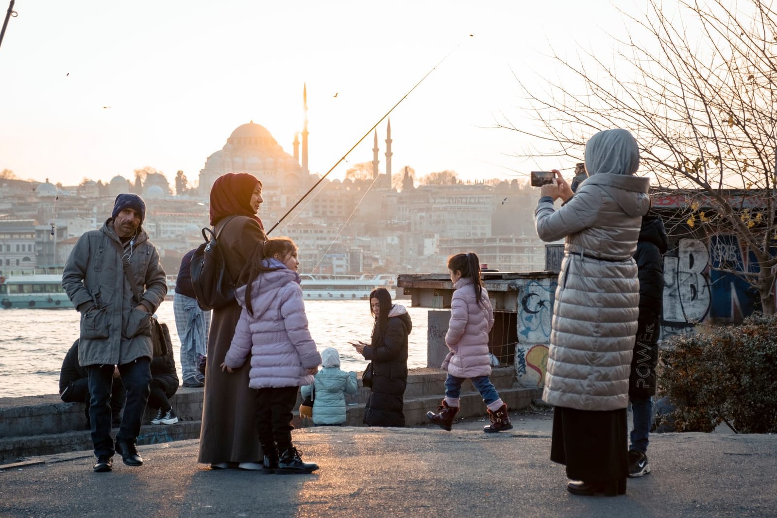 Familie mit Kindern genießt die Aussicht am Wasser auf die Moschee.