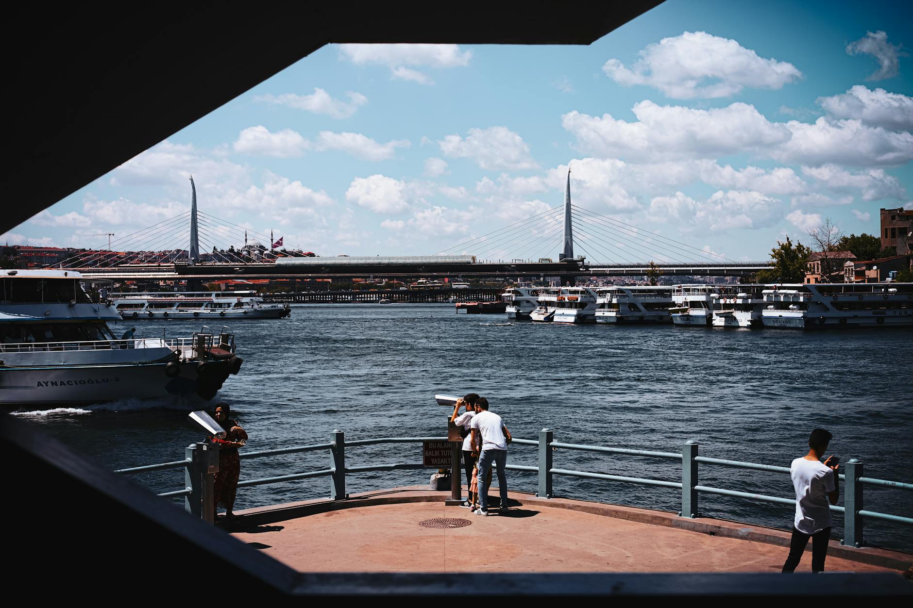 Blick vom Ufer auf das Goldene Horn in Istanbul mit Fähren und der Yavuz-Sultan-Selim-Brücke im Hintergrund.