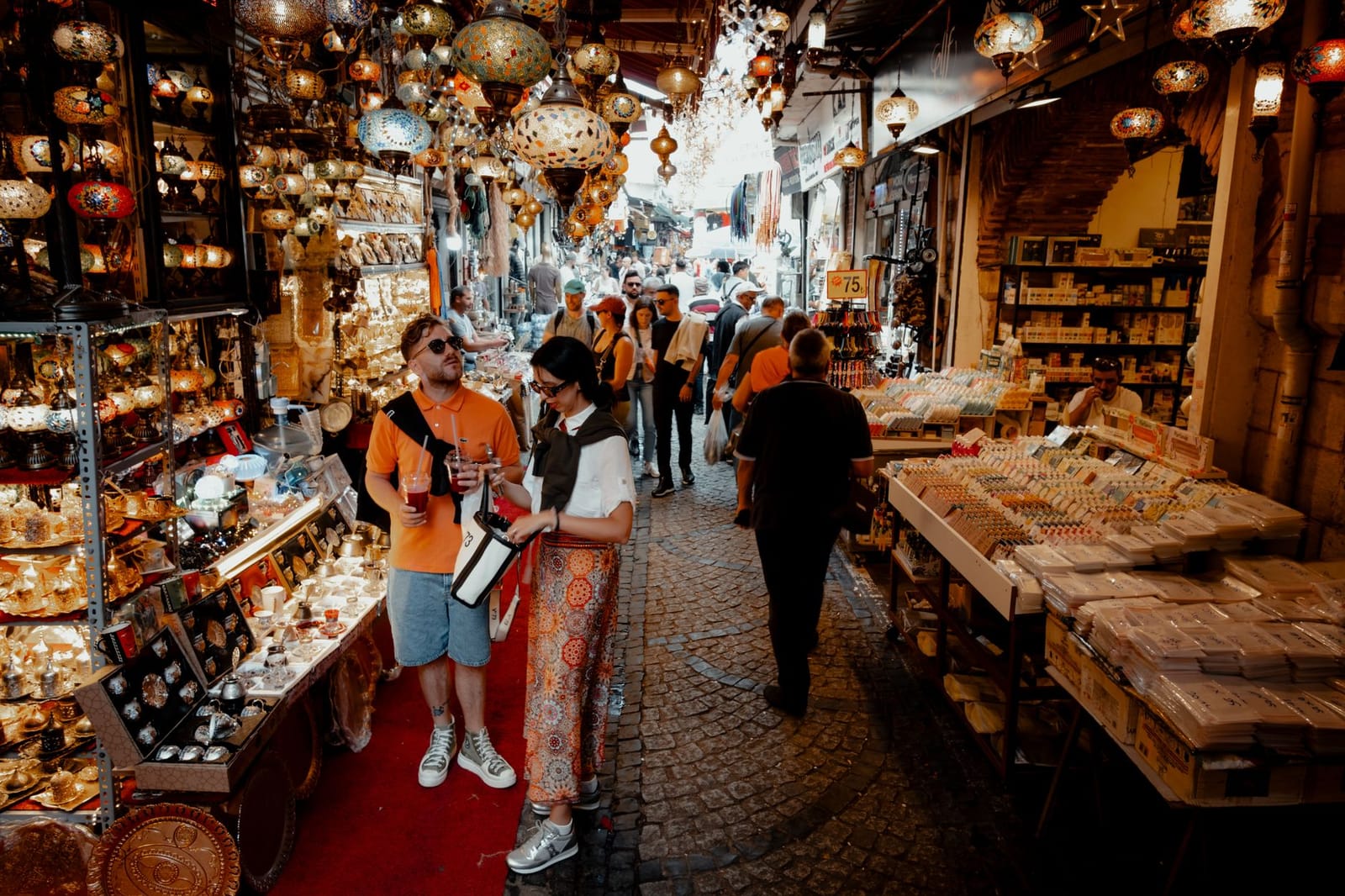 Touristen stöbern durch bunte Mosaiklampen und typische Souvenirs auf einem Basar in Istanbul.