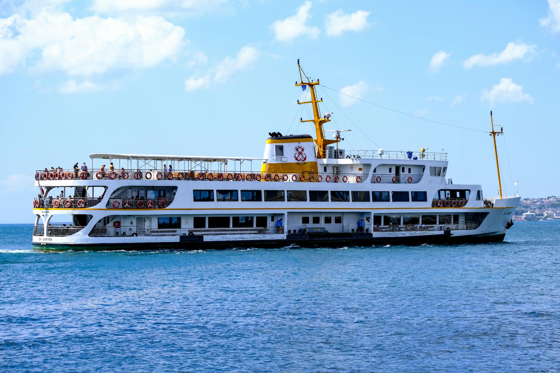 Weiß-gelbe Fähre der Şehir Hatları mit Passagieren auf dem Wasser des Bosporus in Istanbul an einem sonnigen Tag.