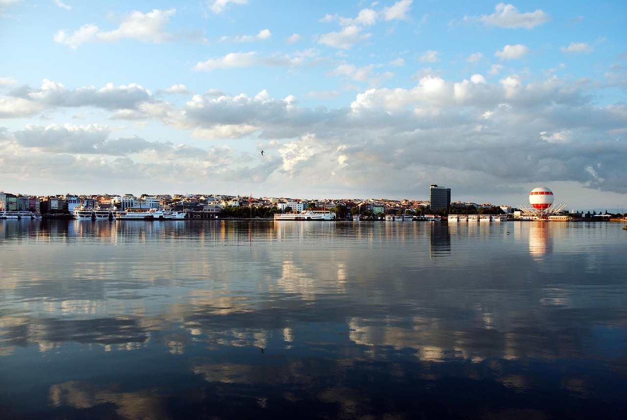 Die Uferpromenade von Kadiköy spiegelt sich im ruhigen Wasser unter einem blauen Himmel.