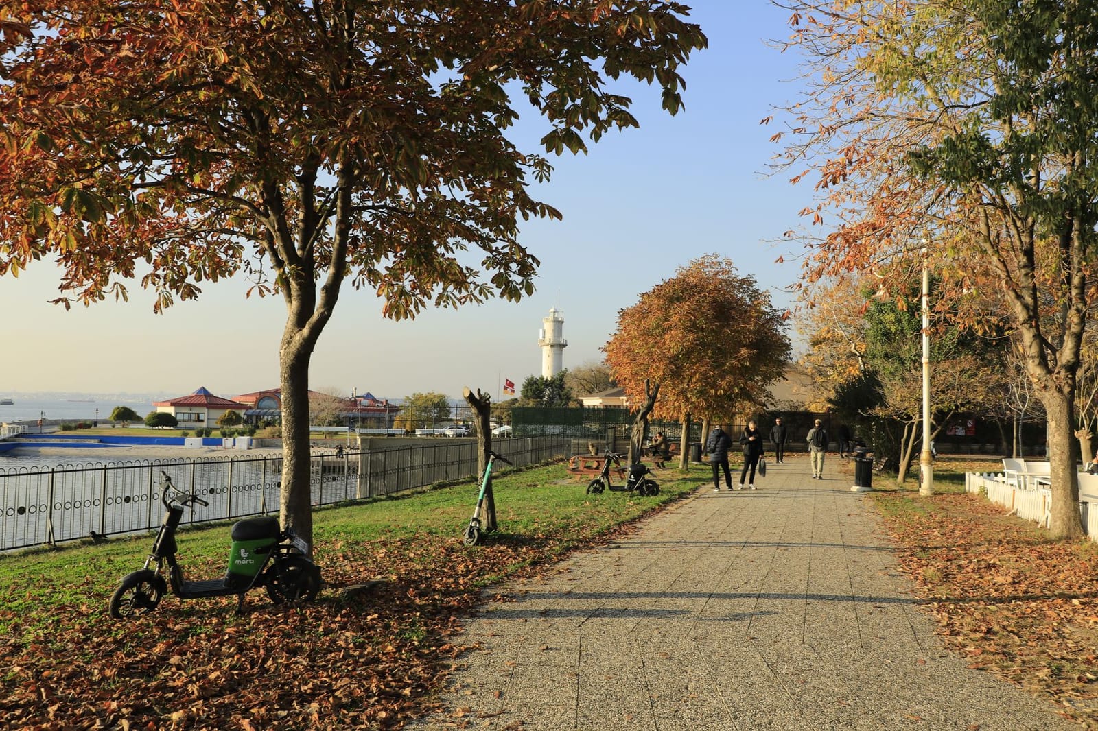 Ein Martı-Scooter steht an einer Promenade mit Leuchtturm im Hintergrund in Istanbul.