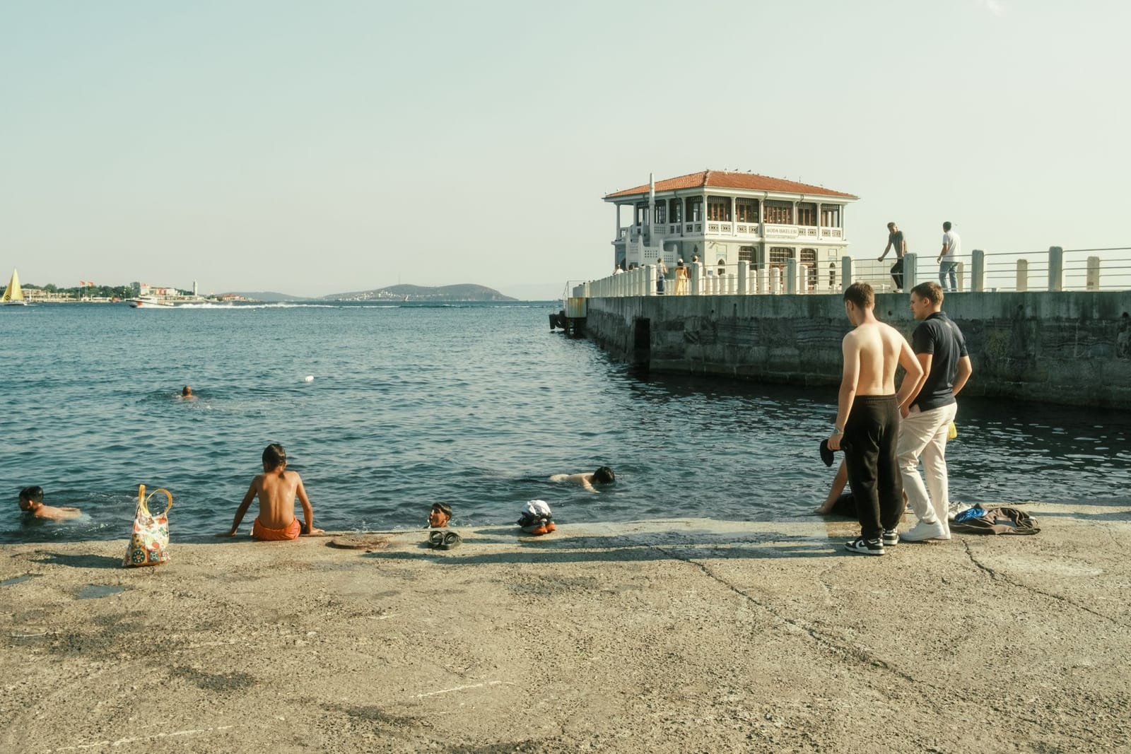 Badegäste schwimmen im Sommer am historischen Fähranleger von Moda in Istanbul.
