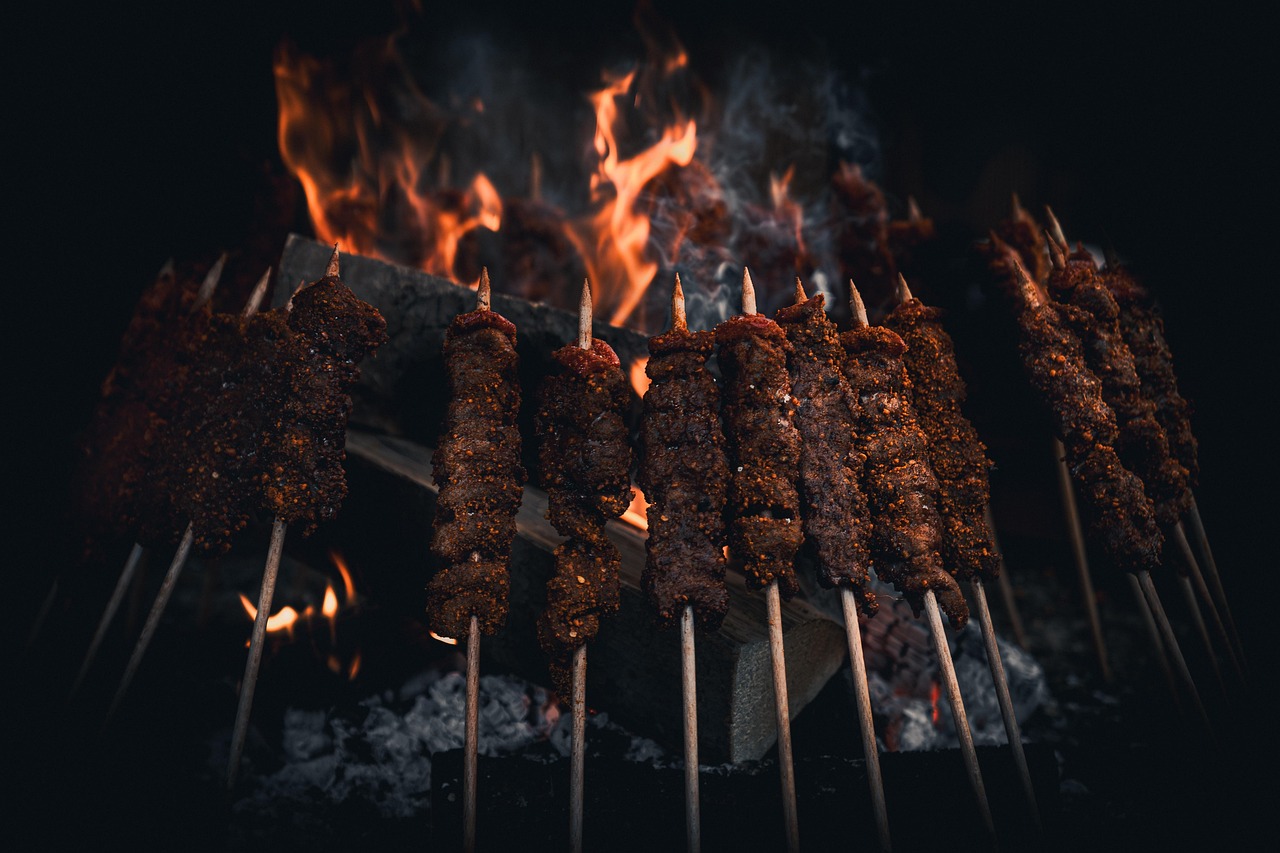 Würziger Cağ Kebab auf kleinen Metallspießen wird über glühenden Kohlen gegrillt.