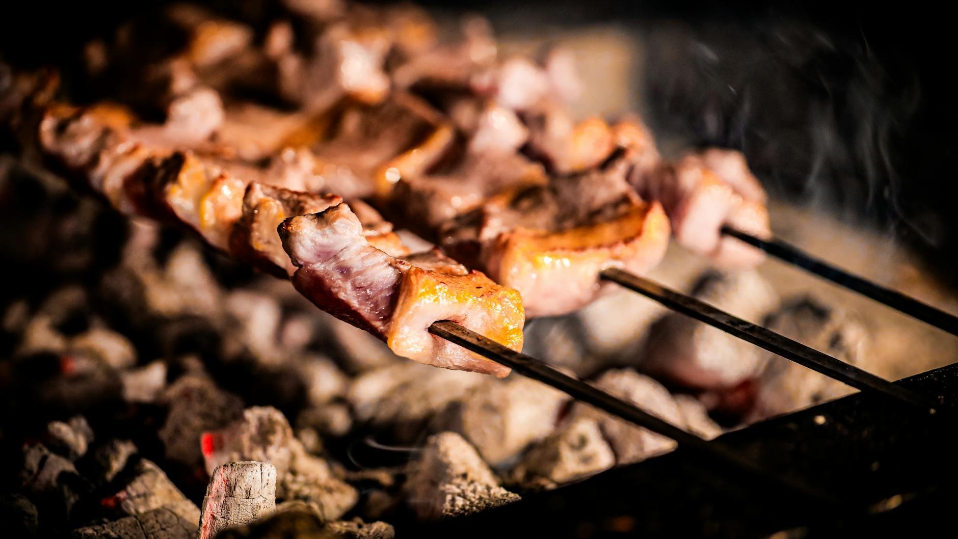 Würziger Cağ Kebab auf kleinen Metallspießen wird über glühenden Kohlen gegrillt.