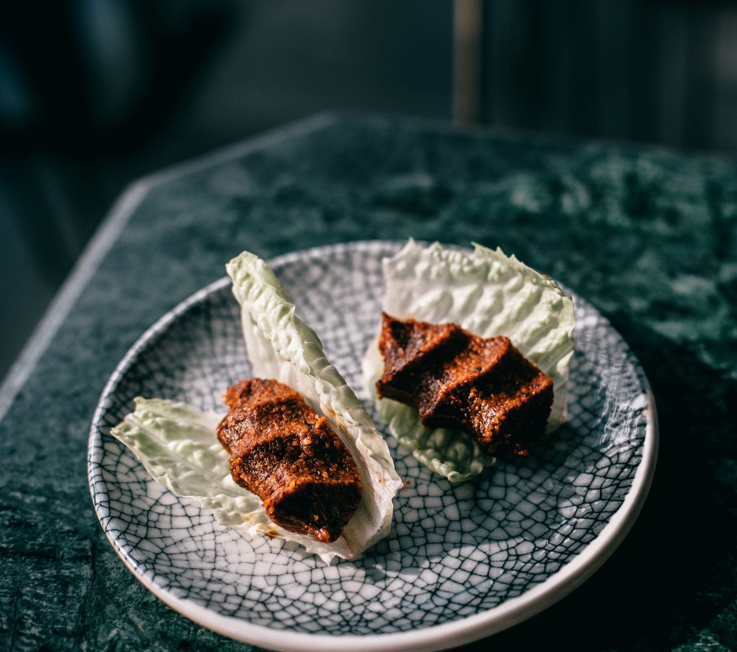 Zwei Portionen traditionelle Çiğ Köfte serviert auf frischen Salatblättern.