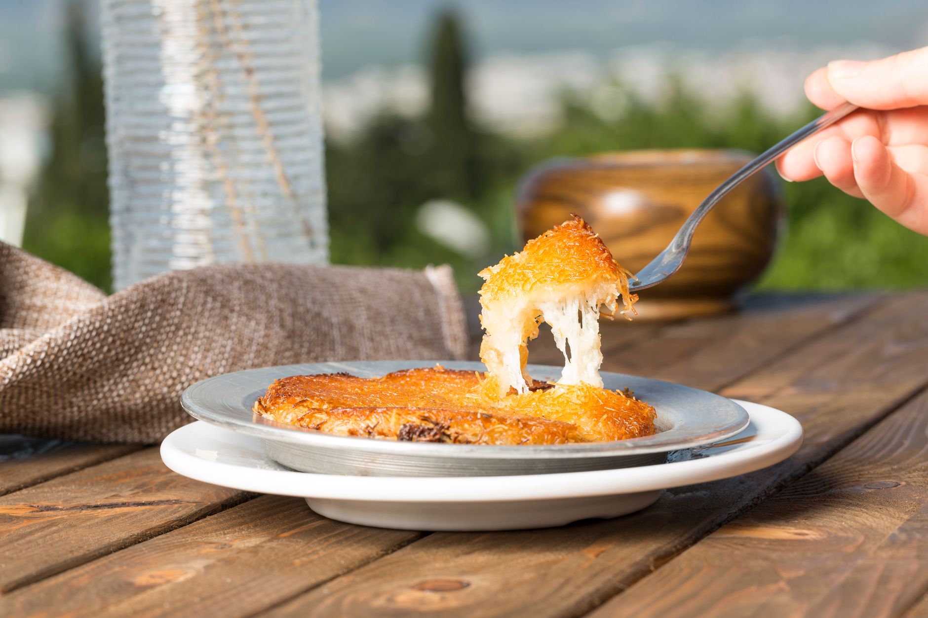 Frisch zubereitetes traditionelles Künefe mit ziehendem Käse auf einer Metallplatte.
