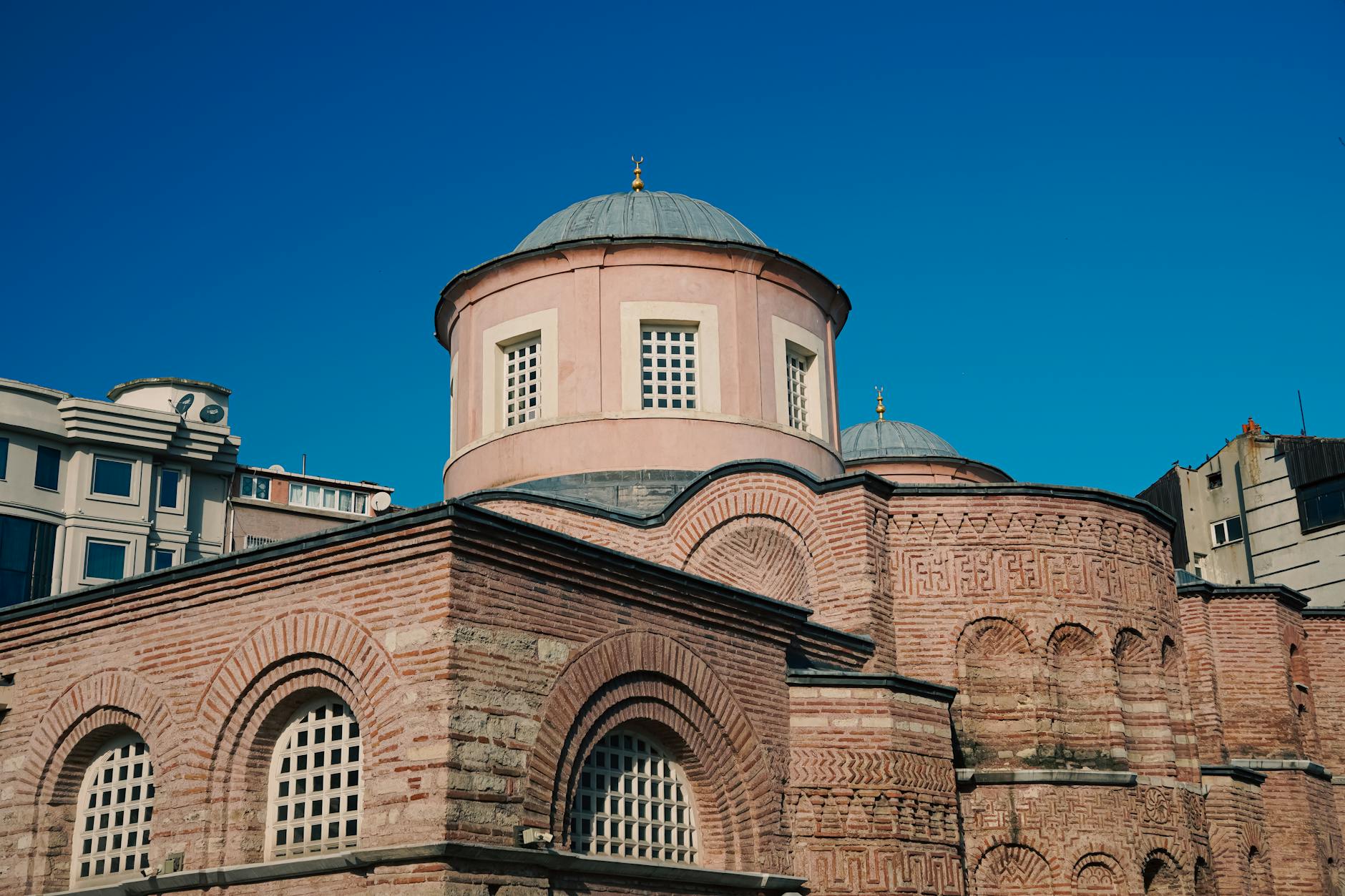 Detailaufnahme der Backsteinarchitektur der Zeyrek-Moschee unter strahlend blauem Himmel.